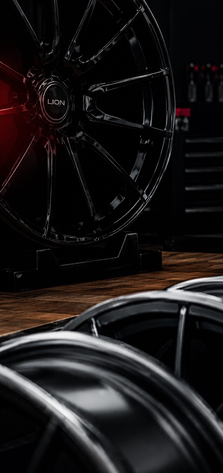 Gloss black alloy wheel on a stand in the workshop
